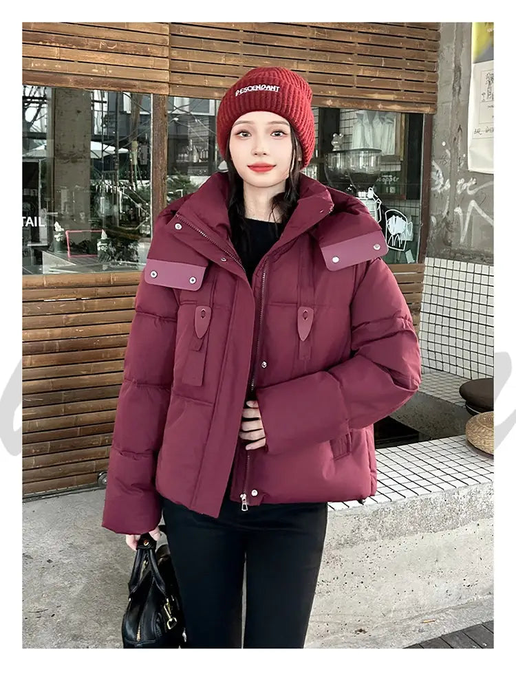Veste courte matelassée bordeaux, confortable et volumineuse, à capuche pour femme, avec un design matelassé et des poches à rabat contrastantes de couleur pourpre, pour l’habillement d’hiver chaud.