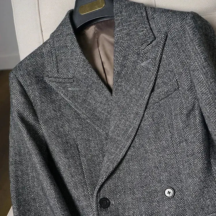 A double-breasted gray herringbone wool British vintage woolen coat slim tweed blazer with black buttons and a satin-lined interior.