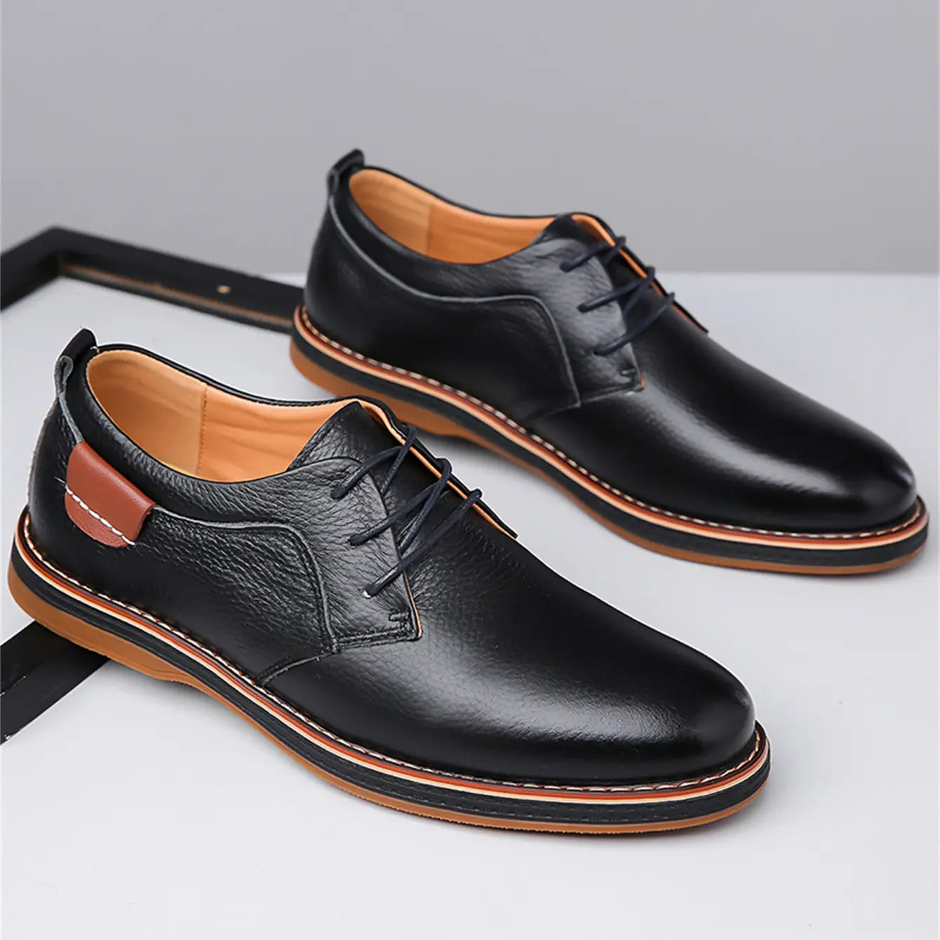 Men’s handmade genuine black leather lace up oxford shoes featuring tan stitching and a contrasting brown heel tab shown from the back.
