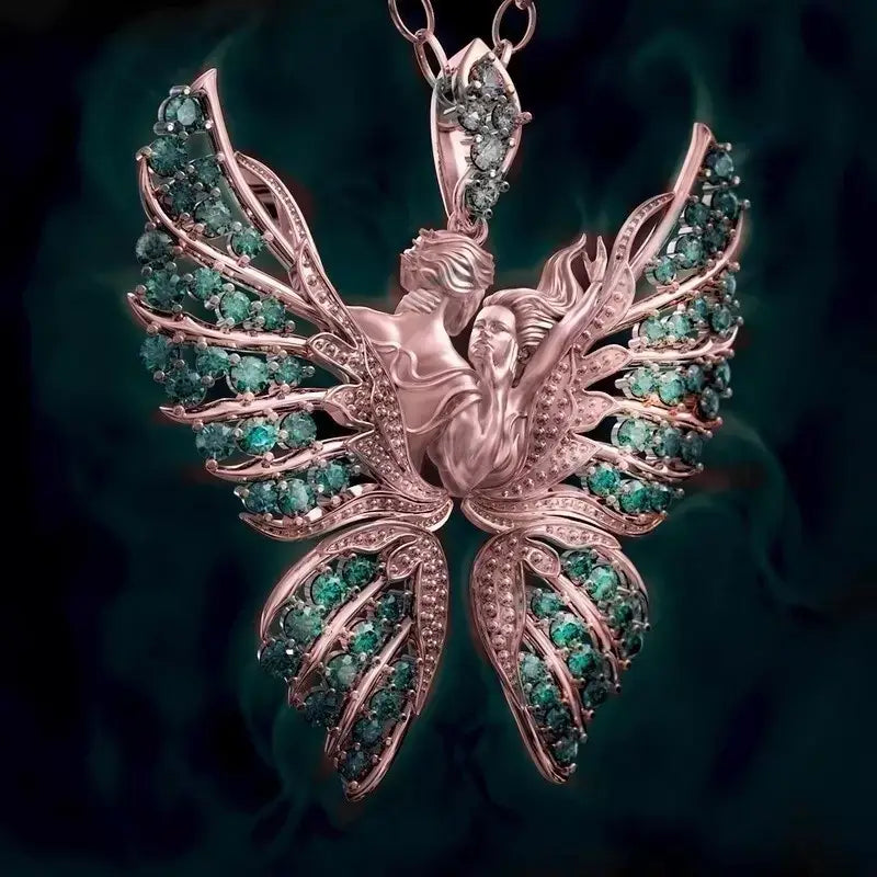 A rose gold emerald angel wing butterfly pendant necklace featuring an intricately designed angel with outstretched wings adorned with emerald green and clear gemstones.