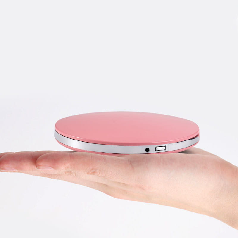 Calentador circular portátil USB en color rosa con borde metálico plateado, mostrado junto con un espejo de maquillaje LED portátil USB compacto plegable.