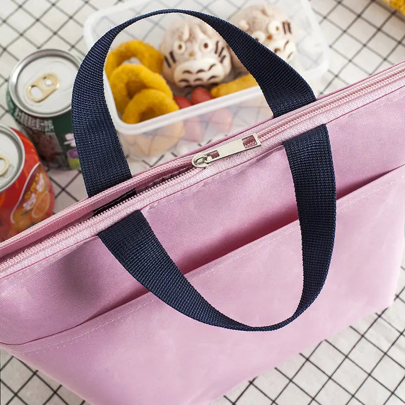 Isolierte Oxford-Bento-Lunchbag in Pink mit dunkelblauen Stoffgriffen und silbernem Reißverschlussverschluss.
