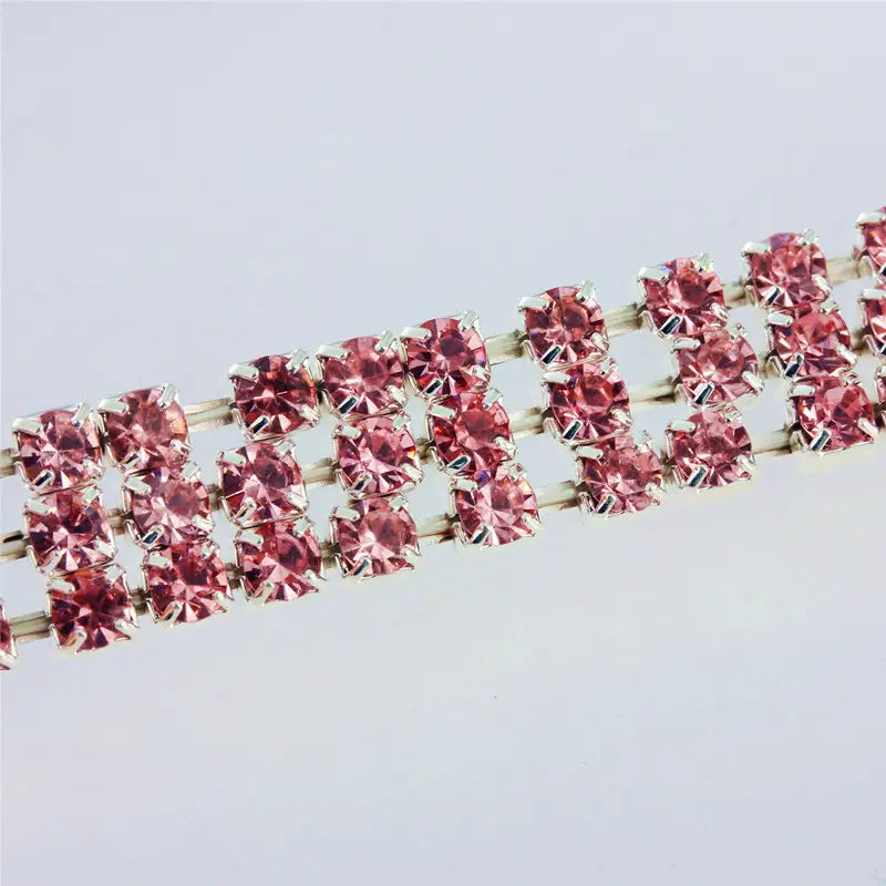 Un collier pour animal de compagnie en strass roses scintillant à motif de patte, avec une base métallique à tons argentés.
