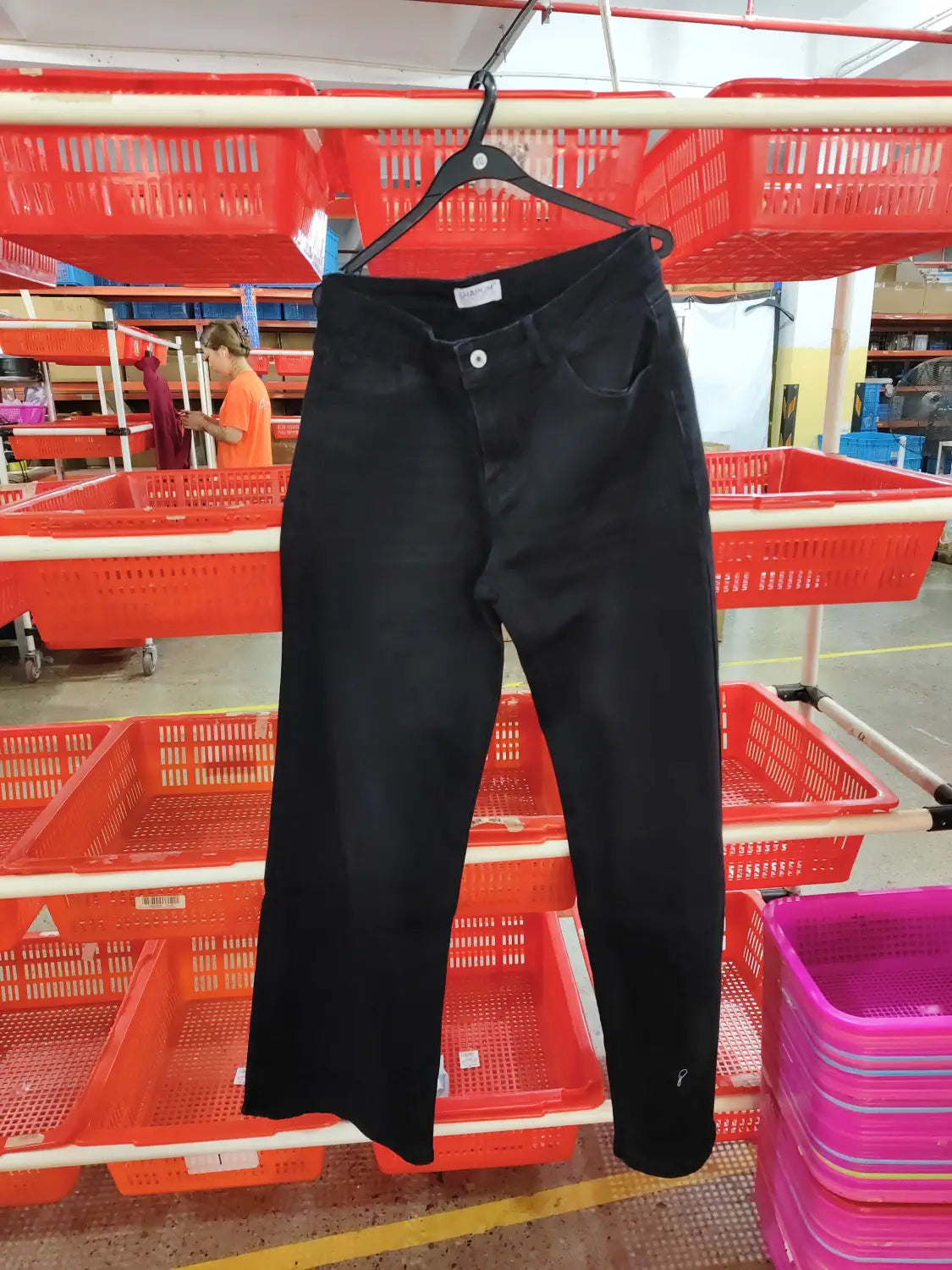 Black denim jeans with a straight-leg cut and classic five-pocket design hanging on a black hanger showcasing wide leg stretch denim jeans.