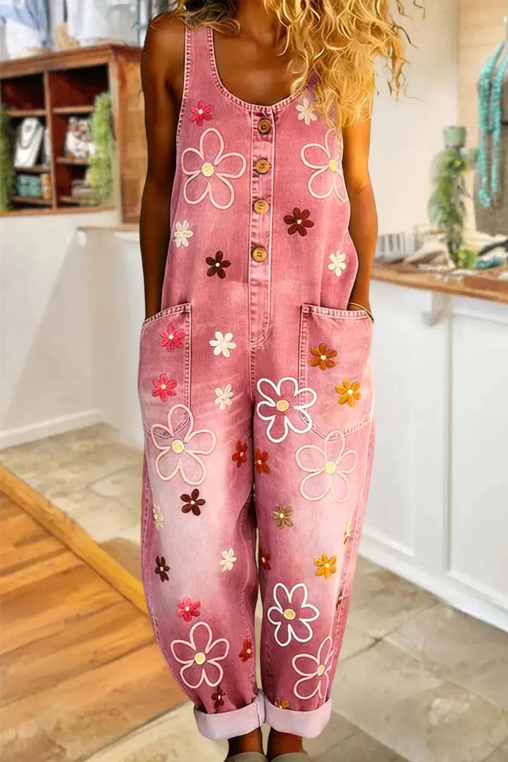 ピンクデニムのオーバーオールは、白・ピンク・ブラウン・イエローのカラフルな刺繍の花をあしらった、ワイドレッグのレトロスタイルです。
