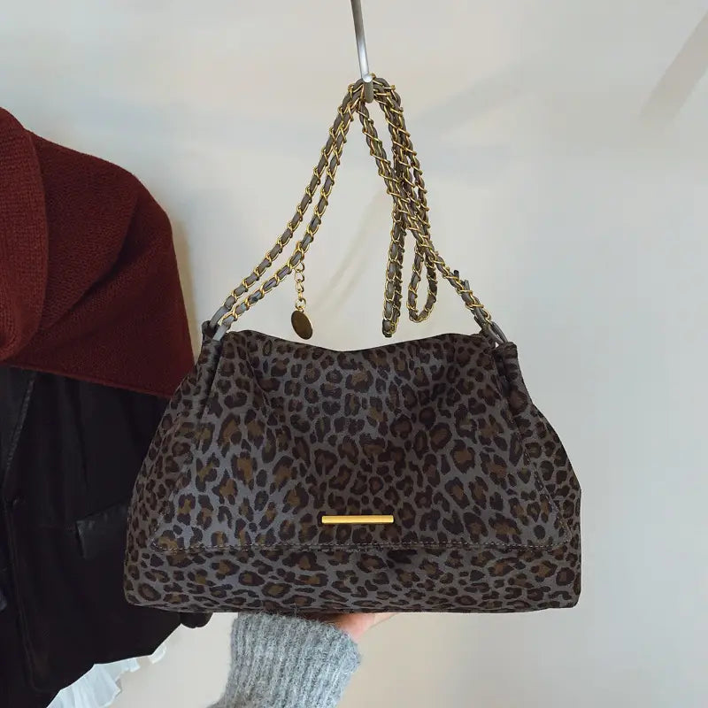 A leopard print crossbody bag in brown and black faux leather with a gold-tone chain strap.