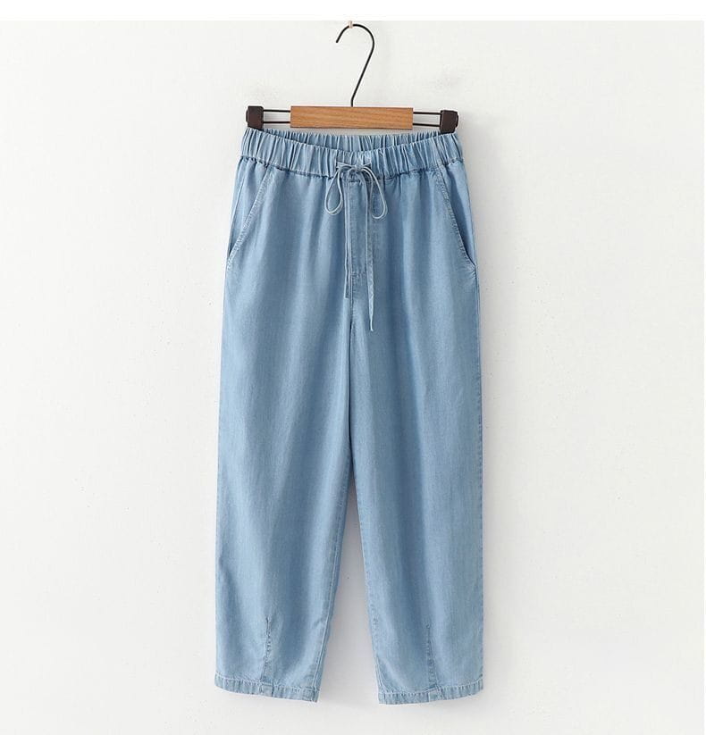 light blue denim harem jeans with a high waisted elastic waist and drawstring closure.