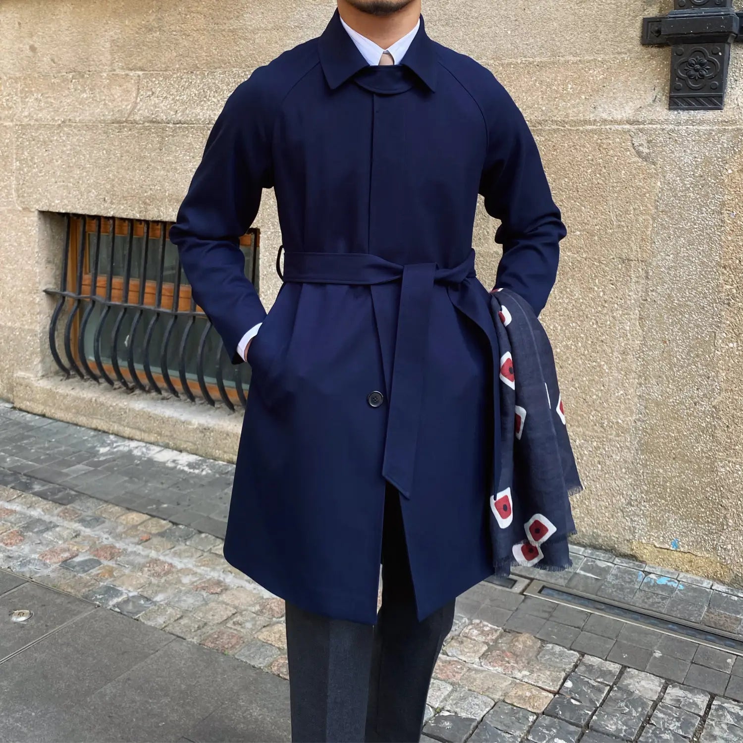 Navy blue belted trench coat with a structured collar and subtle front button detail for winter wear.