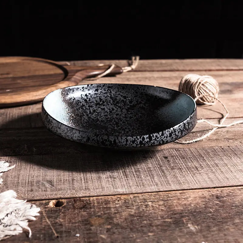 A speckled black ceramic serving bowl with glossy finish and subtle white flecks for home kitchens.