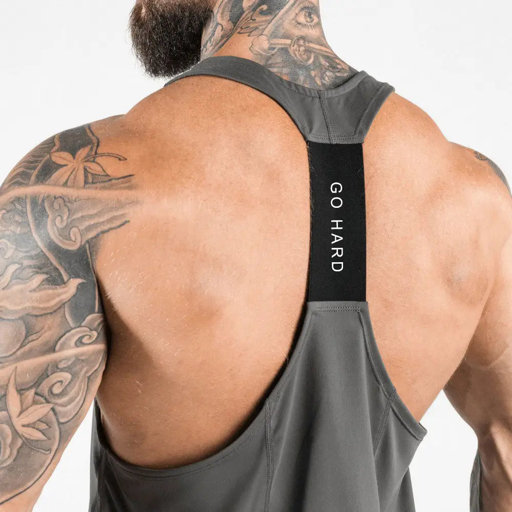 Men’s go hard racerback athletic tank top in gray with black straps featuring white go hard text on the front designed for workout performance.