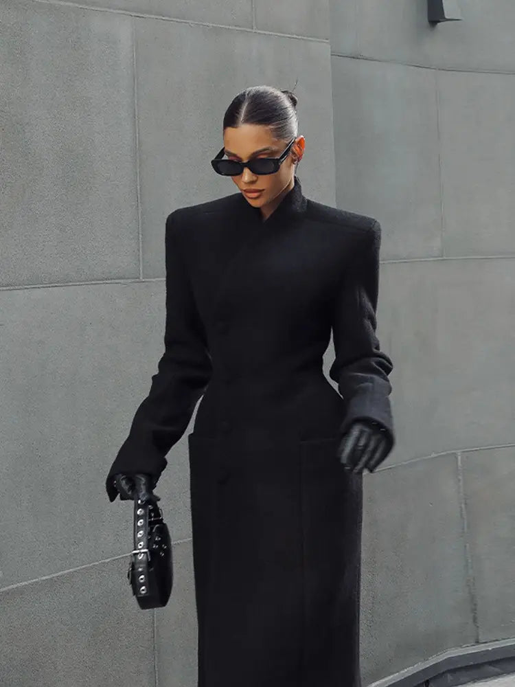Black leather handbag with silver-toned hardware and a structured minimalist design complementing charcoal gray wool coat women waisted long outerwear.