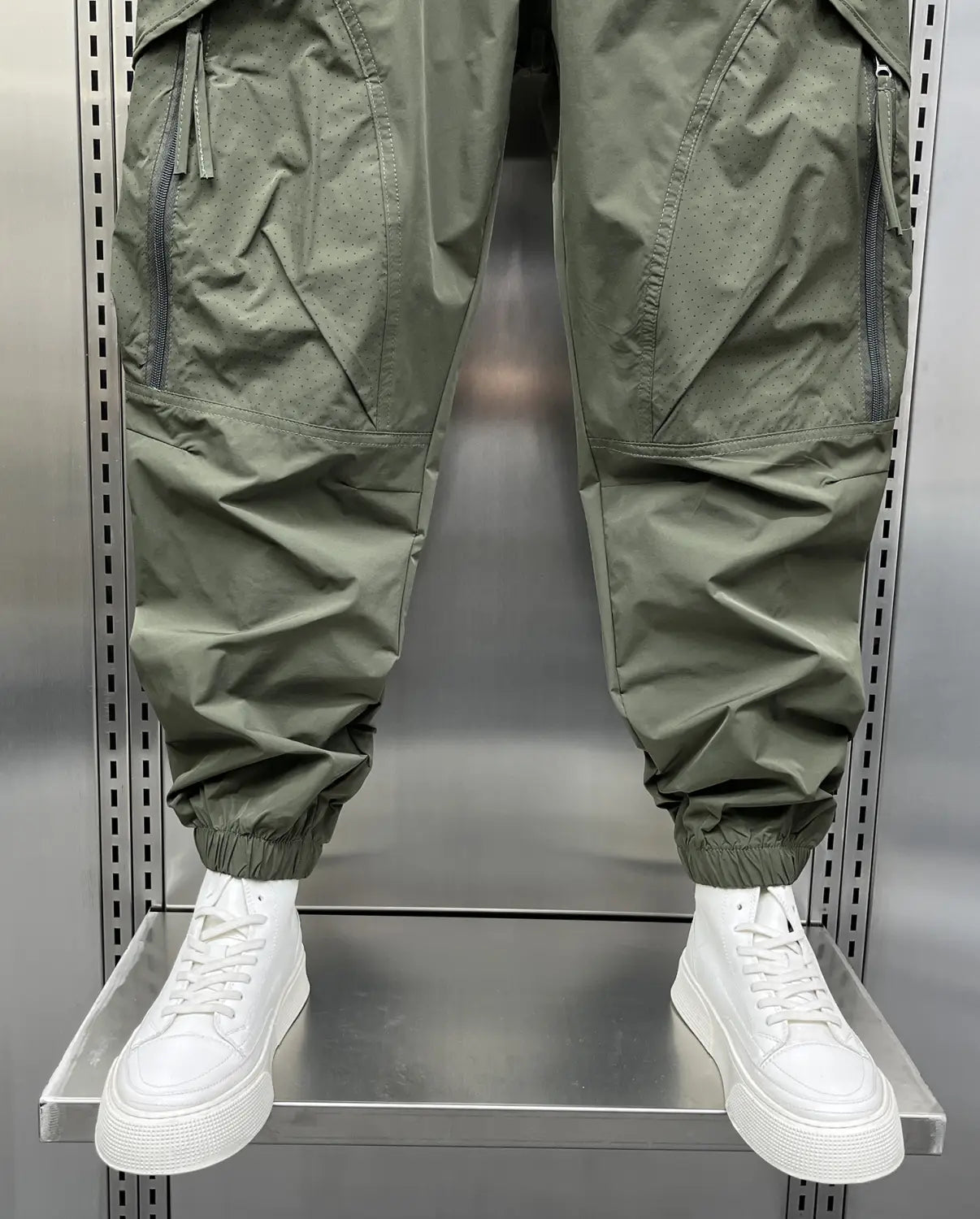 Men’s olive green tapered cargo joggers with elastic waist, multiple zippered pockets, and elastic cuffs.