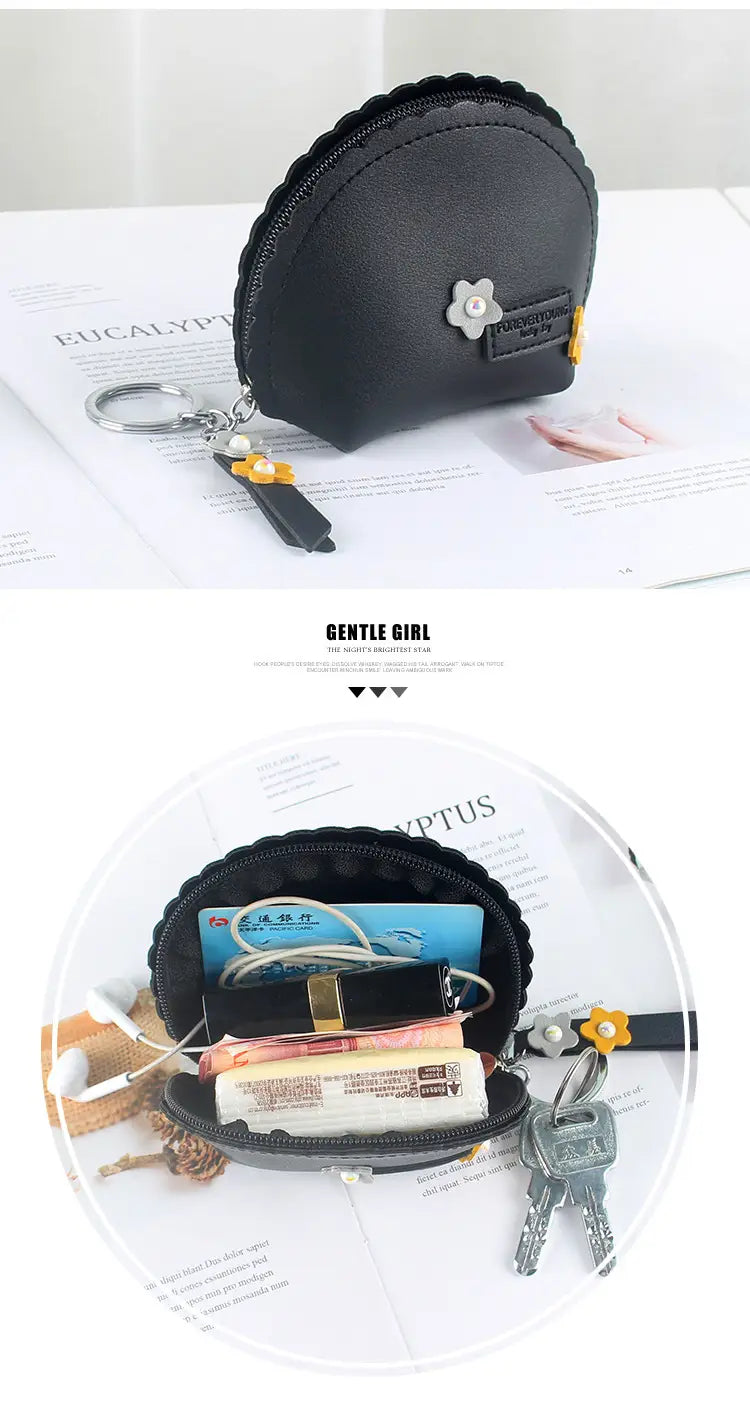 Black shell-shaped pu leather coin purse with silver flower embellishment and yellow accent details with keychain for easy carrying.