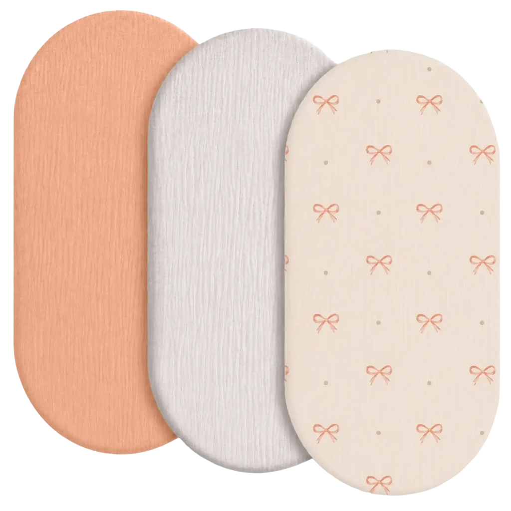Set of three breathable fitted baby crib mattress covers in peach white and cream with textured pink bow patterns