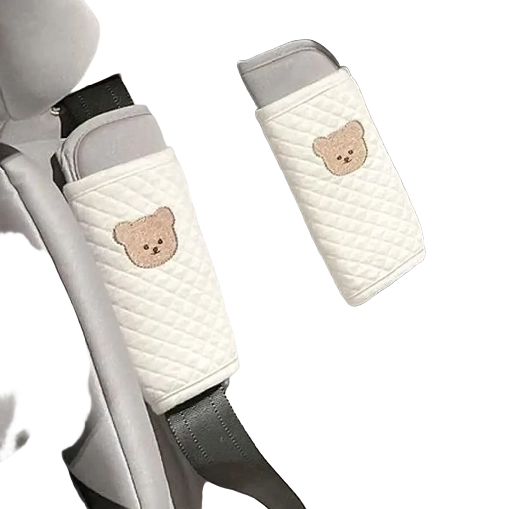 White quilted baby seat belt covers with embroidered beige bear faces designed as animal shoulder pads
