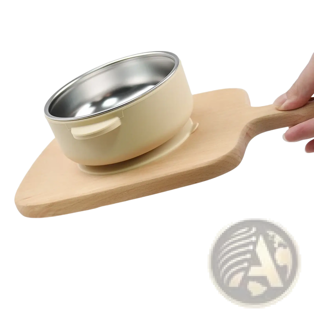 Cream-colored baby training bowl with stainless steel interior and handle resting on a wooden serving board