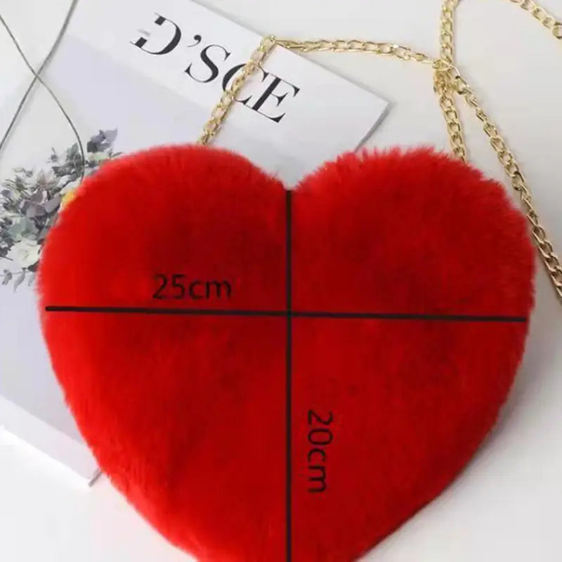 A plush faux fur heart shaped crossbody bag in vibrant red with a gold chain strap.