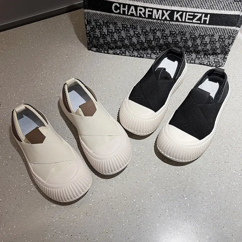 Une paire de baskets décontractées rétro à enfiler pour femmes, respirantes, blanches et noires, avec semelle en caoutchouc côtelée et panneaux latéraux élastiqués pour un enfilage aisé.