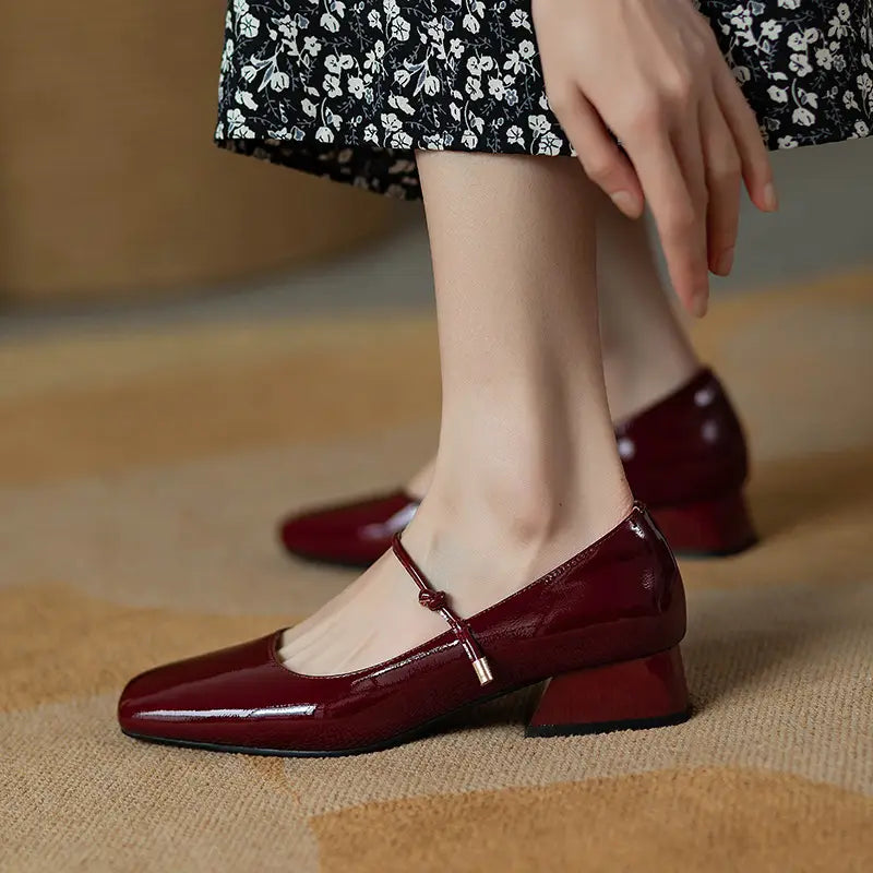 burgundy patent leather mary jane flats with a square toe and low block heel shown from the back side