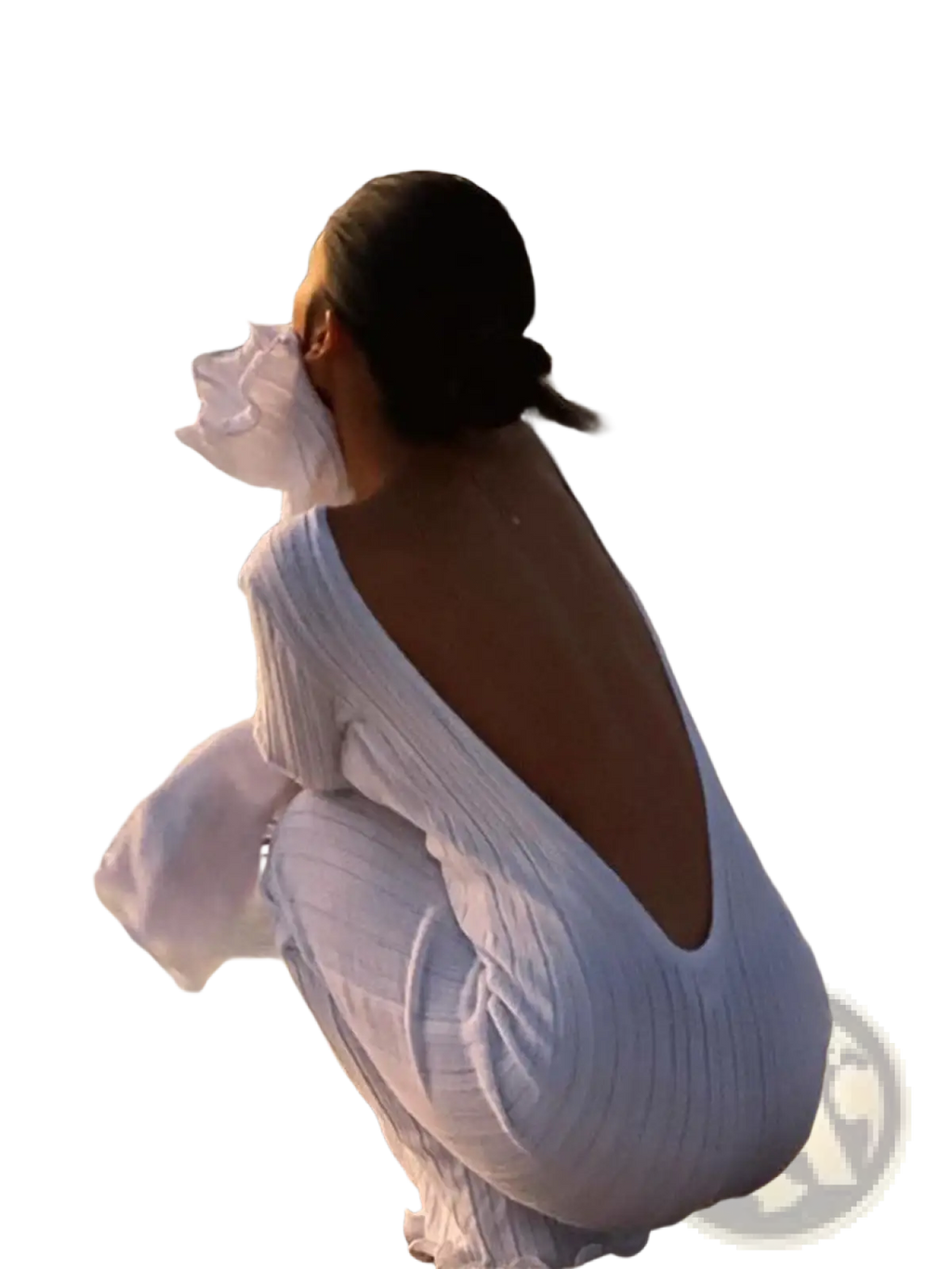 A woman sits on the beach wearing a white ribbed knit backless ruffled bodycon maxi dress with flowing sleeves