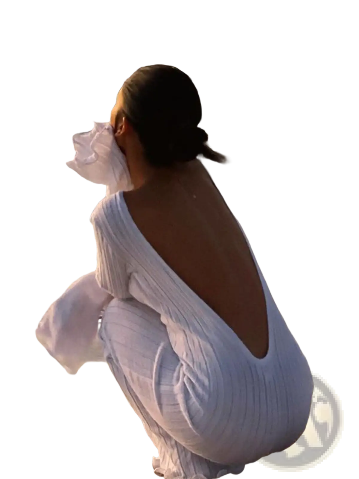 A woman sits on the beach wearing a white ribbed knit backless ruffled bodycon maxi dress with flowing sleeves