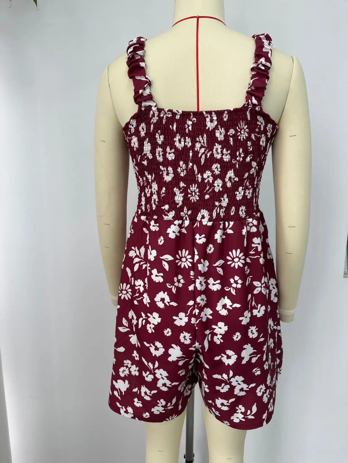 Mono tipo peto burdeos sin mangas con estampado floral para verano en la playa, con flores blancas y tirantes de hombro con frunces.