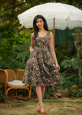 A woman wears a sleeveless vintage badger print olive cotton fit and flare dress with pink and brown floral patterns