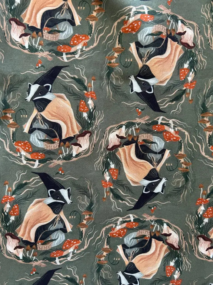 Olive cotton fit and flare dress with vintage badger print featuring black and white badgers in peach cloaks