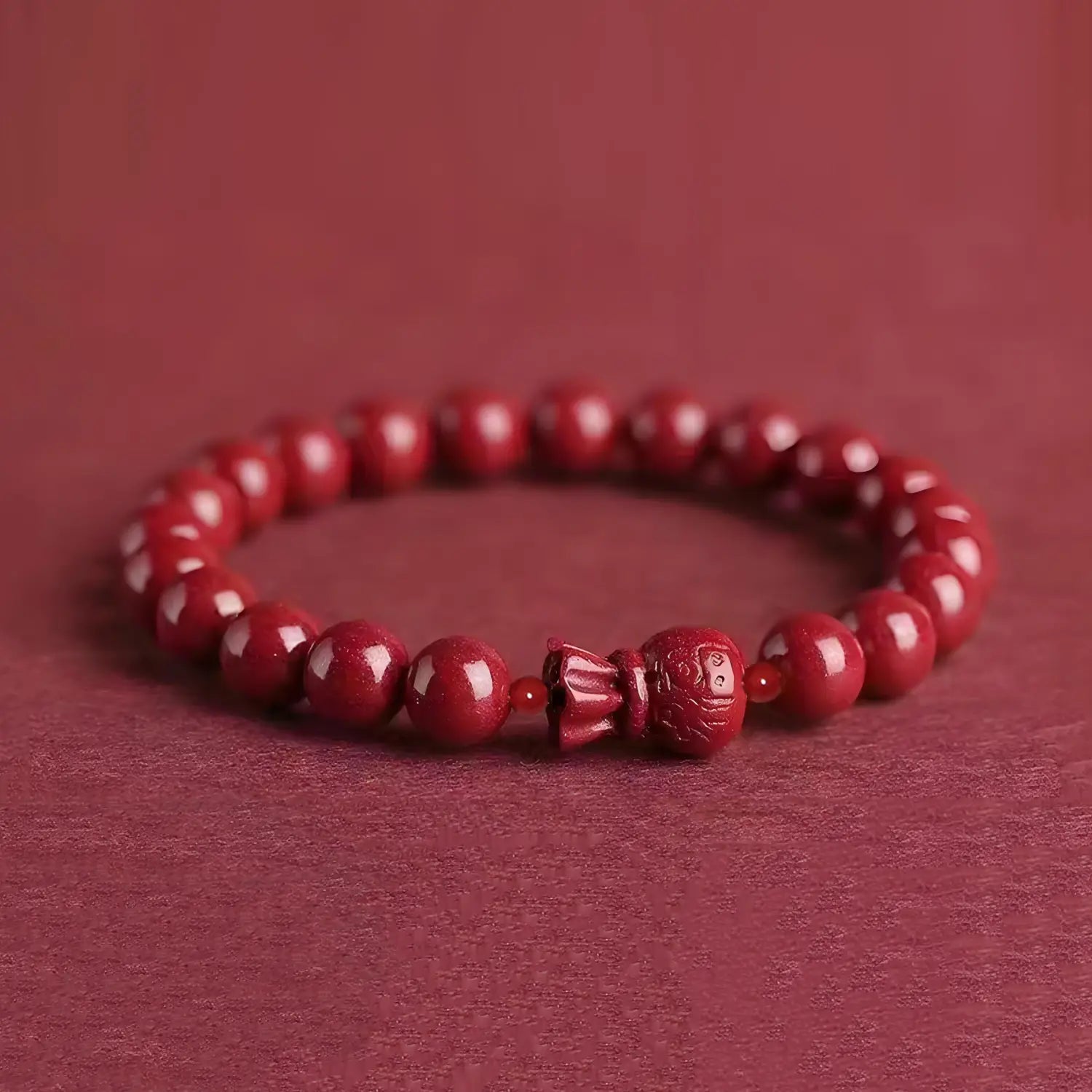 A handcrafted cinnabar lotus and calabash beaded bracelet in polished crimson red featuring a carved buddha figure centerpiece.