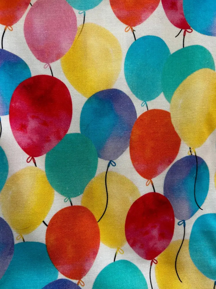 A retro fit and flare dress with a vibrant watercolor balloon print in red yellow blue and green on white fabric