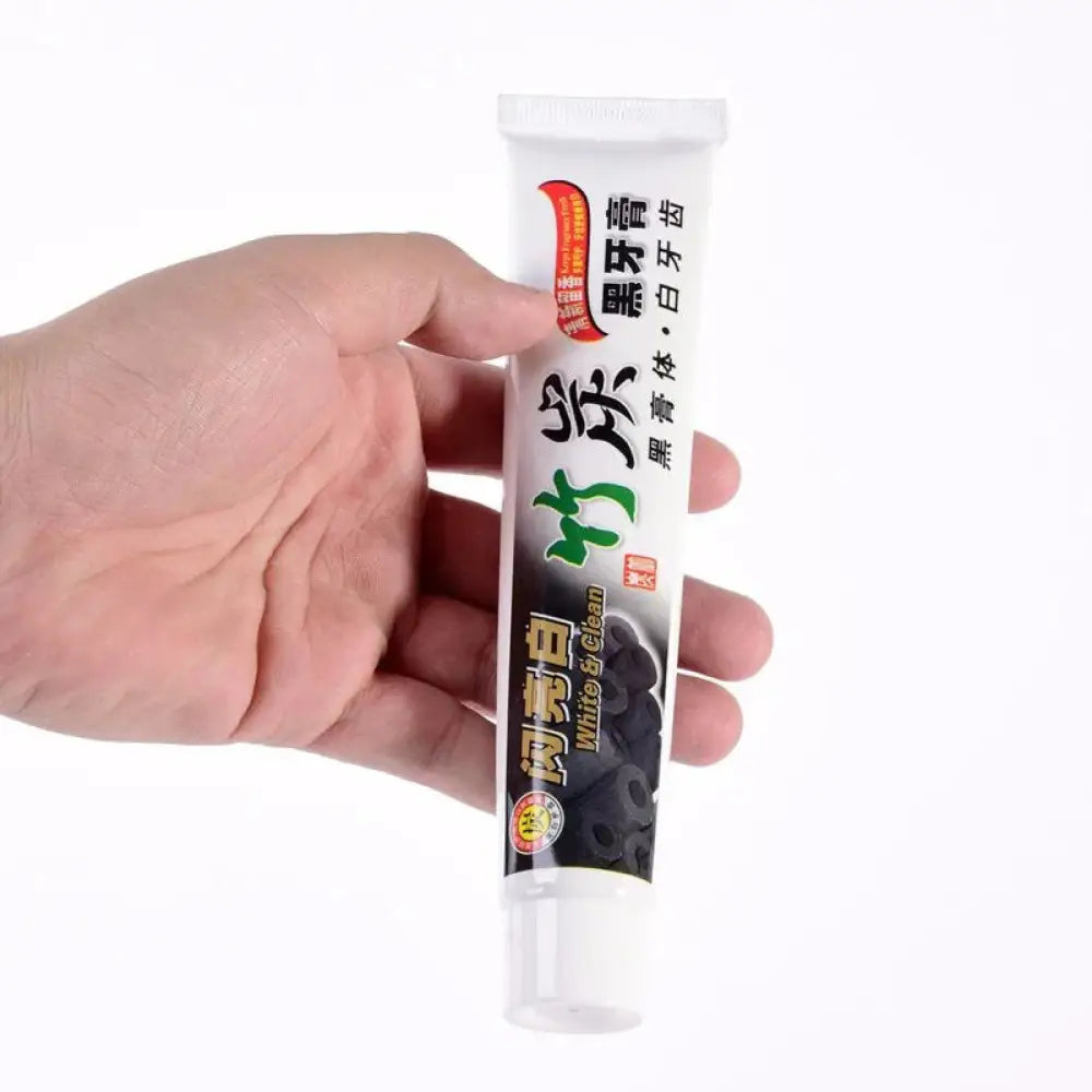 White tube of bamboo charcoal whitening toothpaste with black and green labels featuring dark berries for deep stain removal