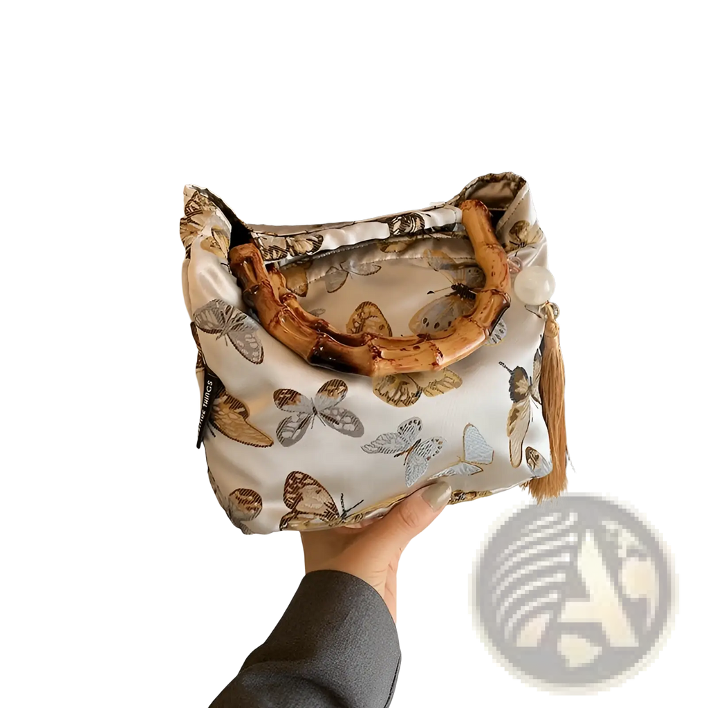 A delicate white bamboo handbag with tassel detail and brown gray butterfly pattern on forest canvas material