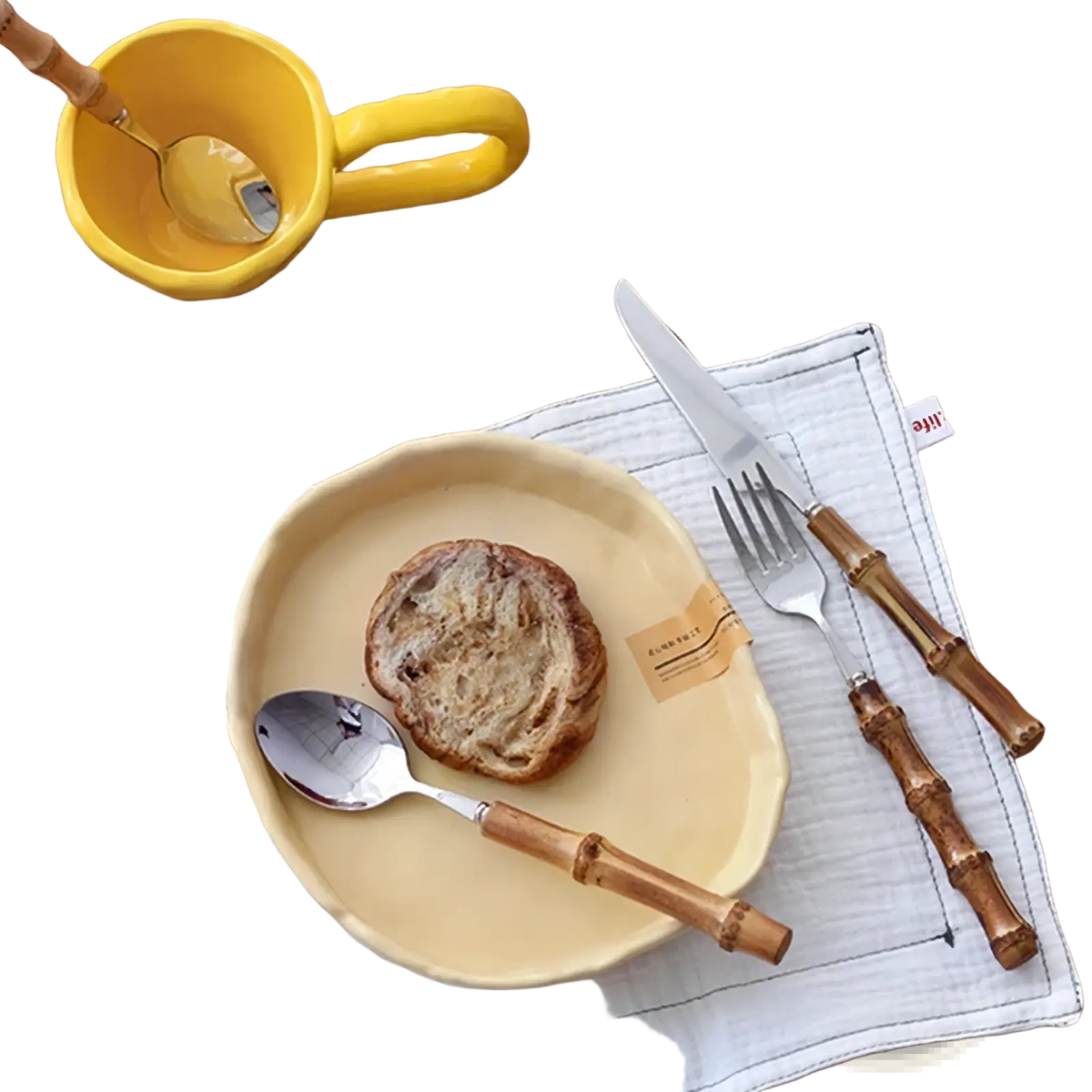 Cream-colored ceramic plate with handcrafted edge paired with bamboo handle stainless steel cutlery set