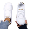 White leather barefoot walking shoes for women with gold accents and fashion branding on the tongue in a minimalist design