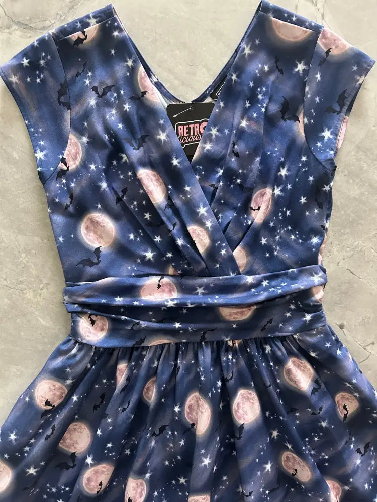 A navy blue vintage cotton sleeveless wrap dress with a celestial print of pink moons black bats and white stars