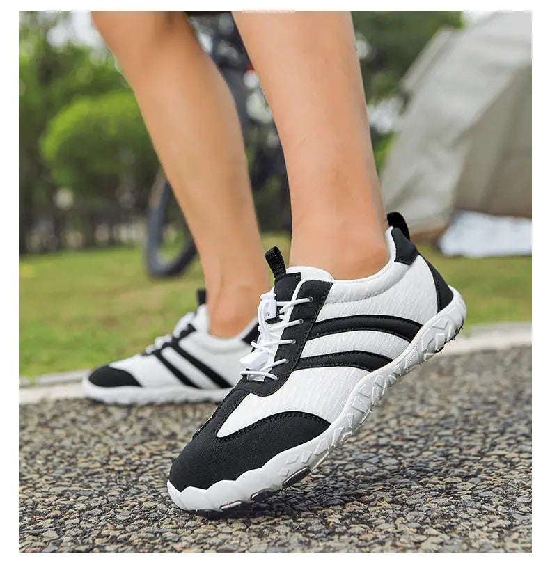white and black wide toe box minimalist running shoes for men and women with a breathable mesh upper, three bold black stripes on the side, white laces, and a rugged rubber sole.