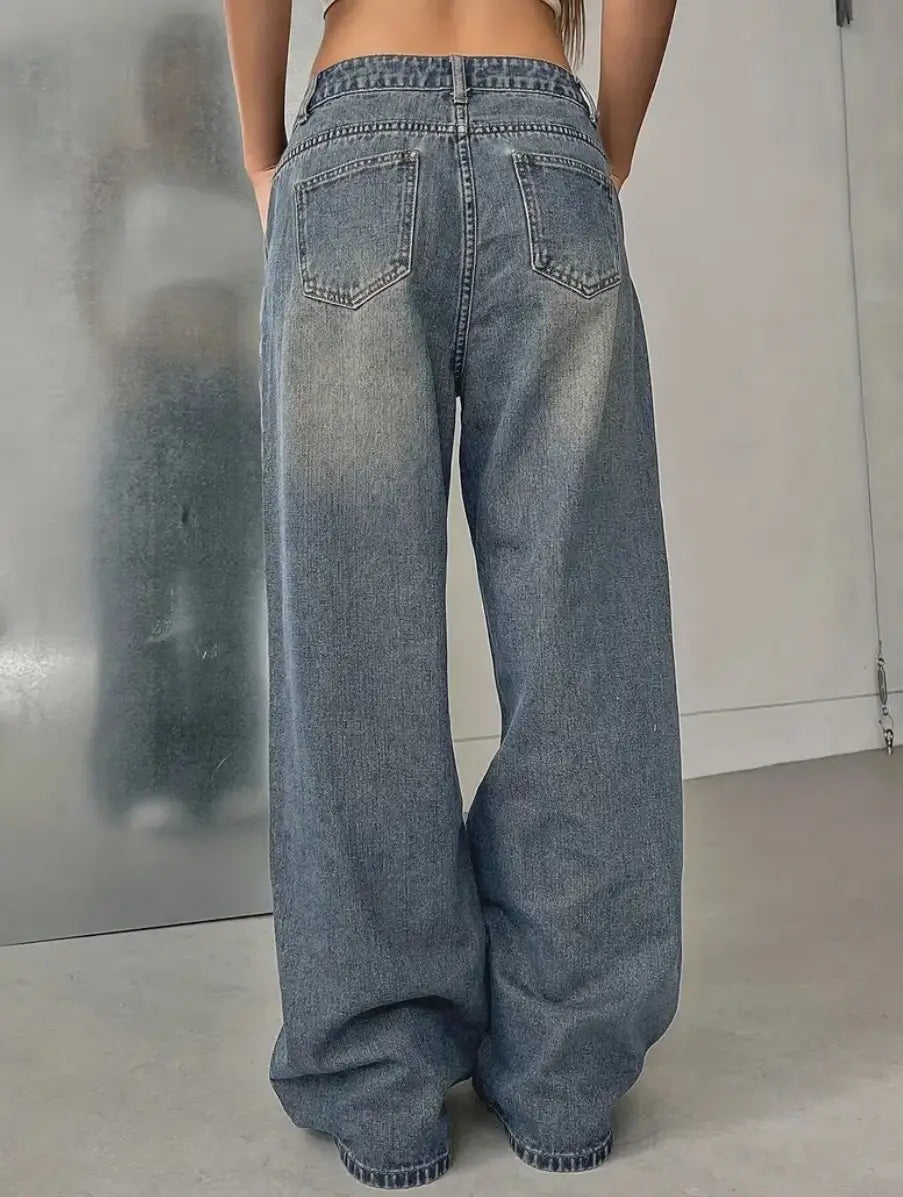 Jeans en denim vintage délavé à jambes larges, délavage bleu délavé, présentant des poches arrière classiques et des finitions cousues.