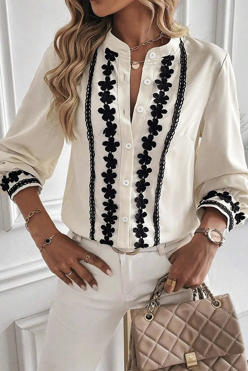 Cream-colored satin blouse with black floral embroidery along the front placket and cuffs featuring lace trim.