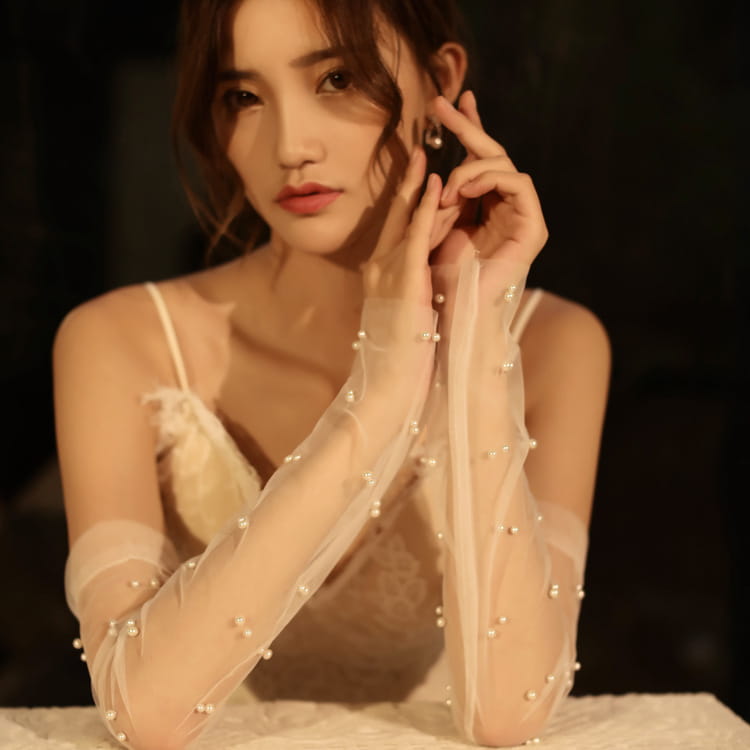 Gants de mariée en tulle transparent, élégamment ornés de perles, présentant de délicats détails de perles le long de chaque doigt.