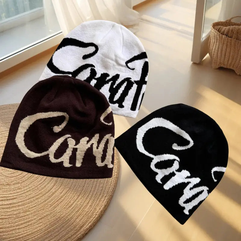 three embroidered letter knit beanie hats in black with white cara lettering and beige with dark brown cara lettering made of soft textured fabric.