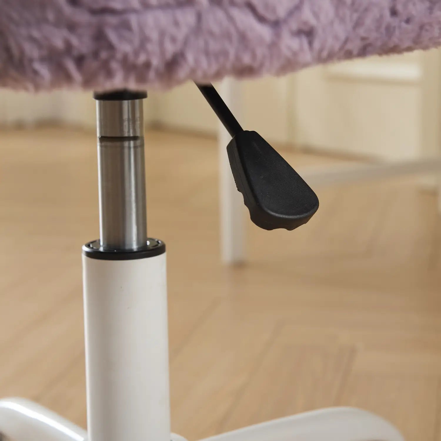 Fauteuil de bureau en fausse fourrure violette avec des roues colorées, avec un mécanisme de réglage de la hauteur argenté sur base blanche.