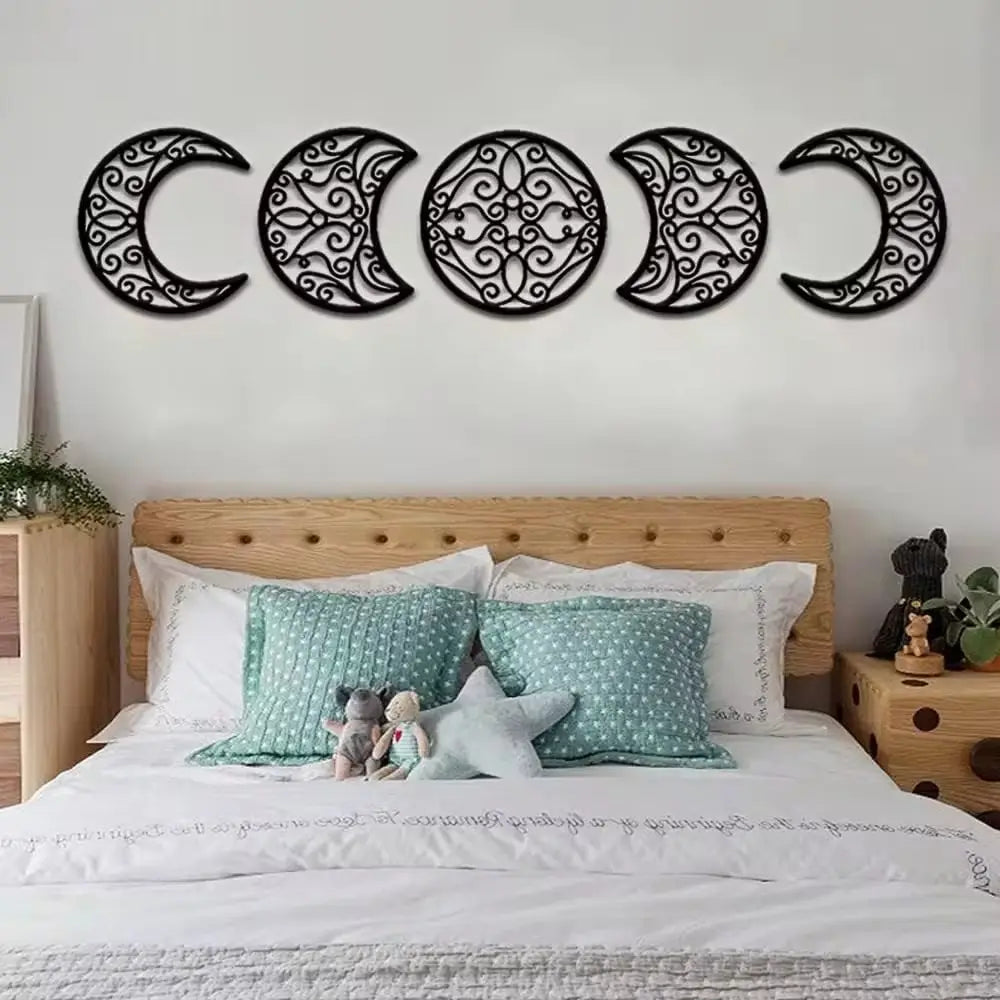 Black metal wall art featuring five intricately designed crescent moons with swirling patterns in a moon phase wall art 5 piece black metal decor set.