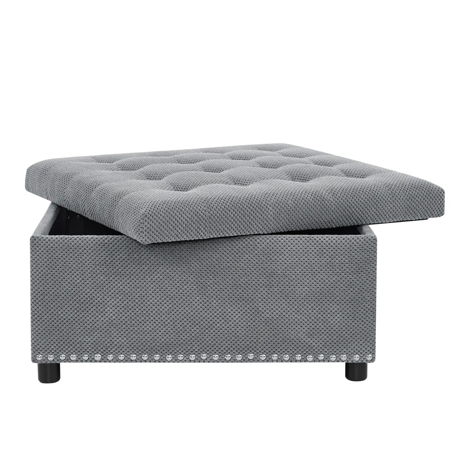 Gray tufted square storage ottoman with textured fabric weave and decorative nailhead trim.