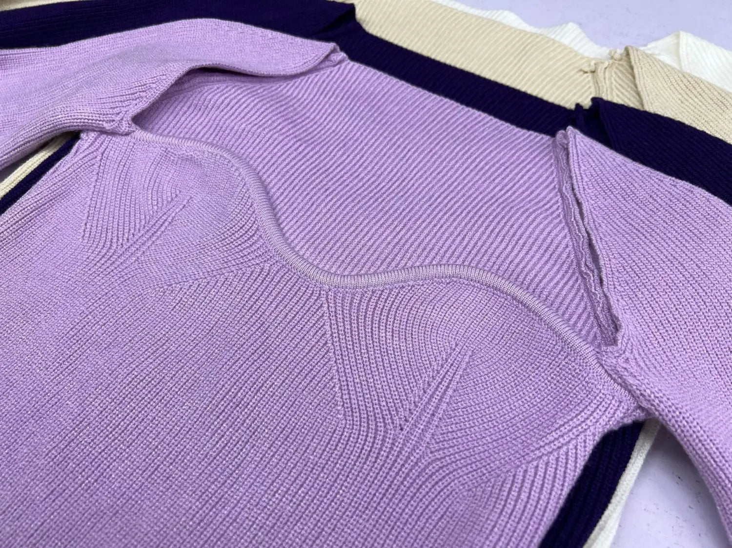A lavender ribbed knit pullover with a structured form fitting design and dark blue trim along the sweetheart neckline.