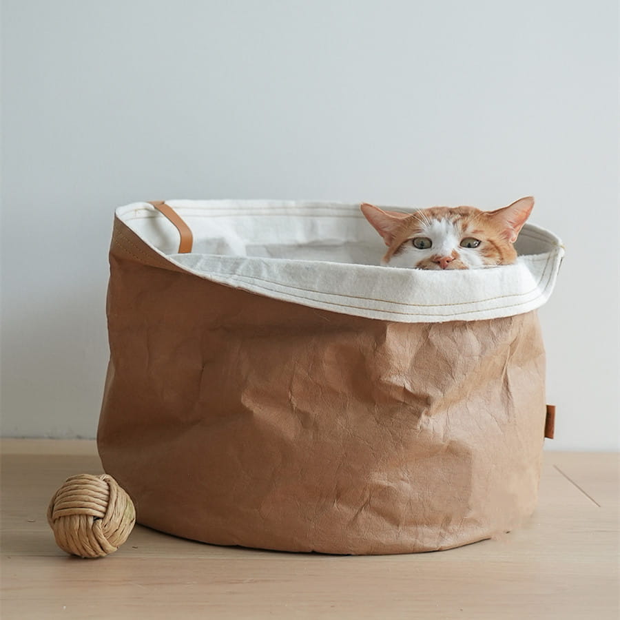 Brown paper pet bed washable round dog cat nest with white interior lining and tan leather handles.