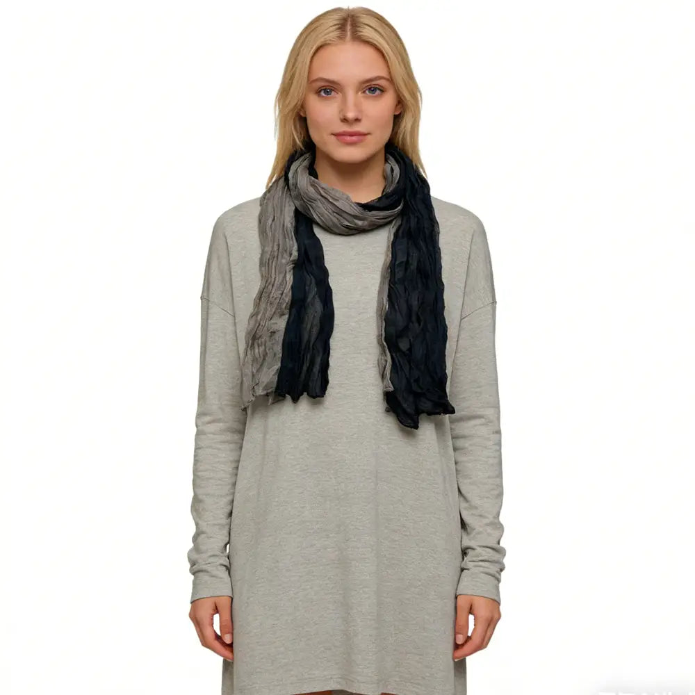 Una bufanda de color gris negro con textura y aspecto arrugado, confeccionada con una tela ligera que presenta una mezcla suave con degradado de tonos grises y negros.