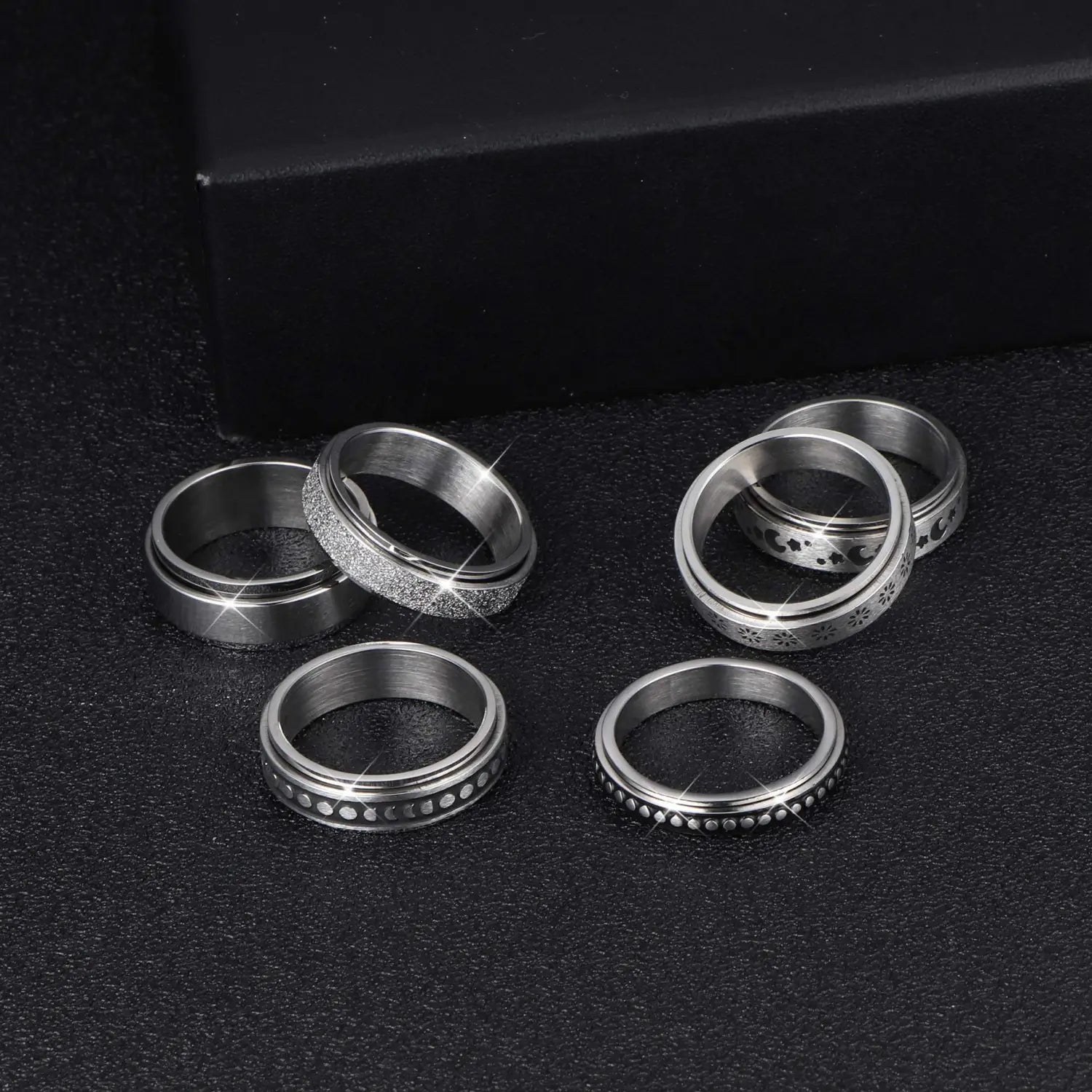 Set of six silver-toned stainless steel anxiety spinner rings with various textured, beaded, and engraved decorative patterns from the Celestial Stainless Steel Anxiety Spinner Ring Set.