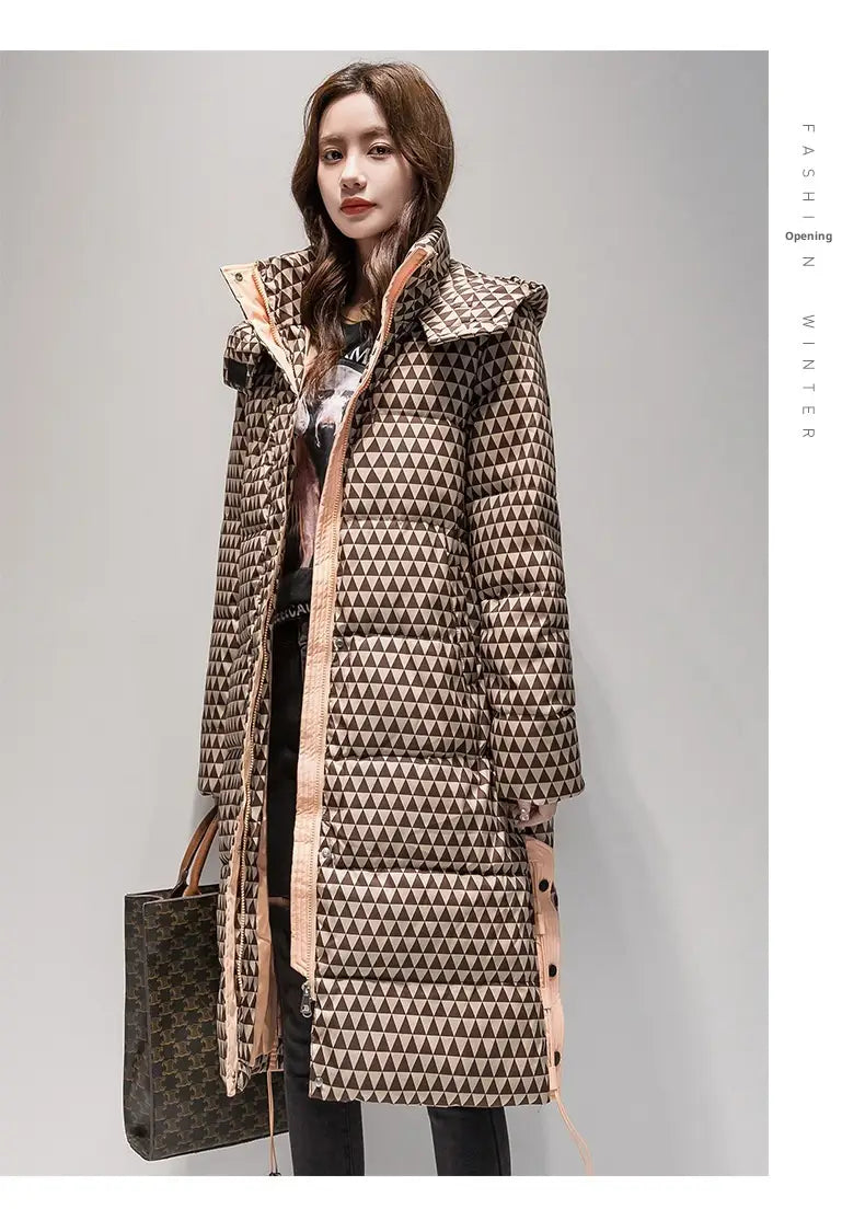 Un long manteau matelassé en coton à carreaux pour femmes avec un motif de triangle géométrique dans des tons de marron et de beige, et une capuche doublée d’une finition rose.