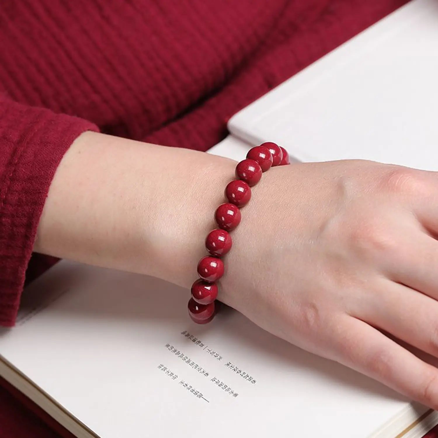 A polished red cinnabar spherical bead bracelet with a vibrant glossy finish worn on a wrist.