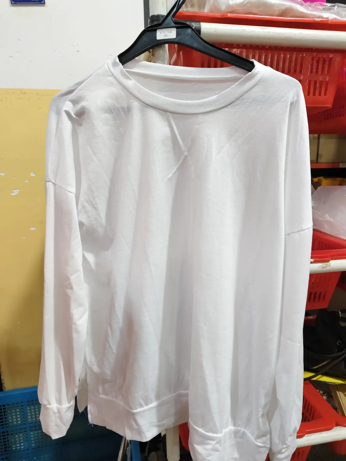 White long-sleeved crewneck split front relaxed knit sweater with ribbed cuffs and a relaxed fit.